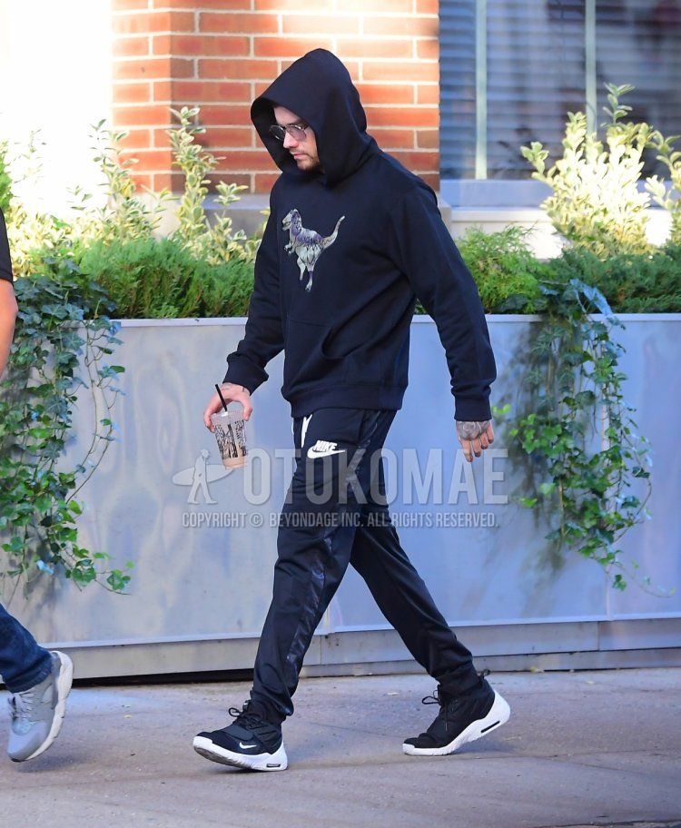 Spring men's coordinate and outfit with plain silver sunglasses, navy graphic hoodie, Nike black one-pointed jogger pants/ribbed pants, and Nike black sneakers.