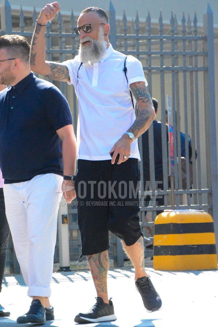 Men's summer coordinate and outfit with plain sunglasses, plain white polo shirt, plain black shorts, and Adidas NMD black low-cut sneakers.