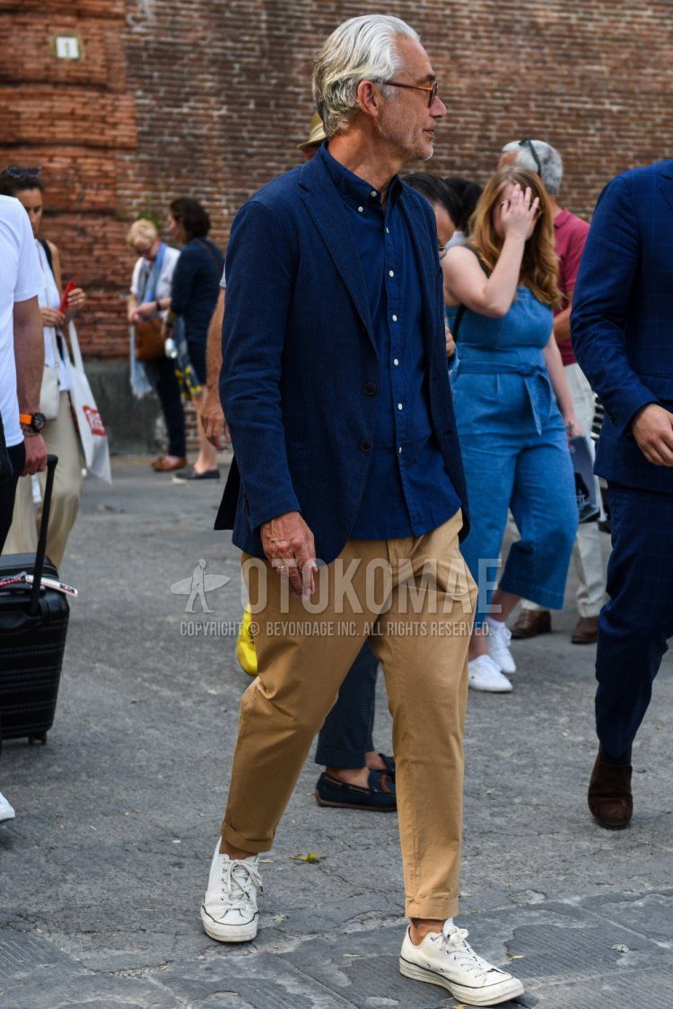 Men's spring, summer, and fall coordinate and outfit with plain navy tailored jacket, plain navy shirt, plain beige cotton pants, and white low-cut sneakers.