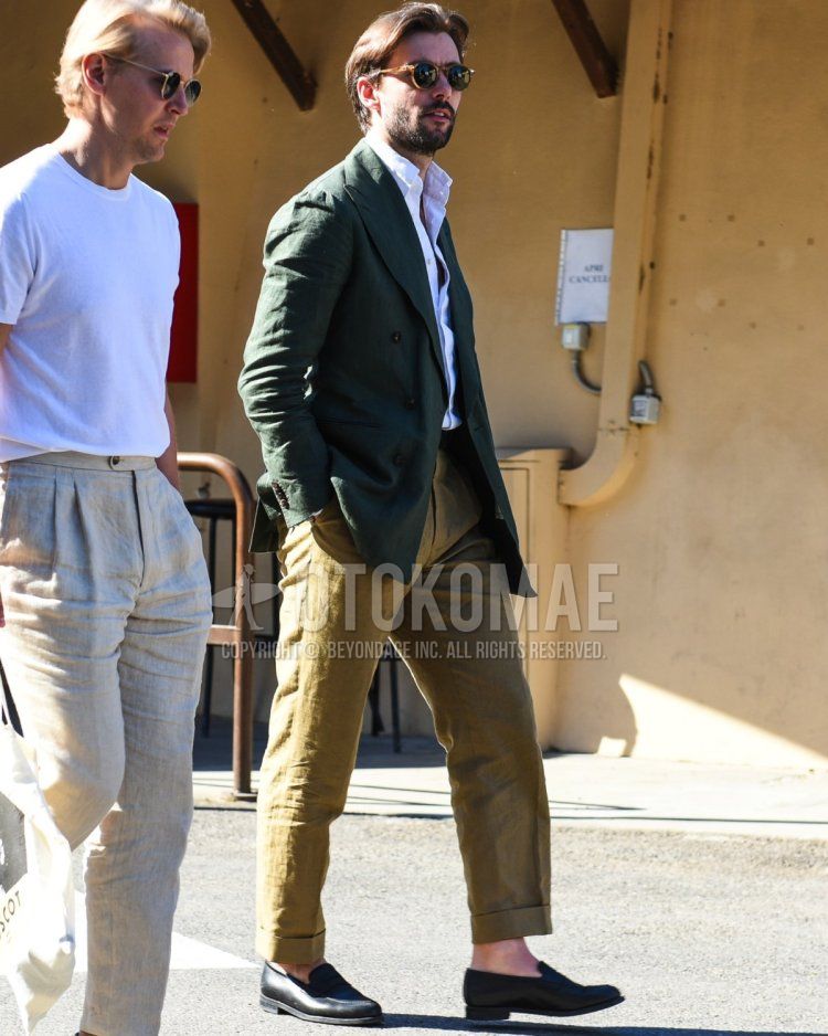 Men's spring and summer coordinate and outfit with brown tortoiseshell sunglasses, plain green tailored jacket, plain white shirt, plain beige chinos, and black coin loafer leather shoes.