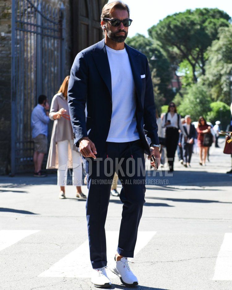 Men's spring/summer coordinate and outfit with plain black sunglasses, plain navy tailored jacket, plain white t-shirt, plain navy easy pants, and white low-cut sneakers.