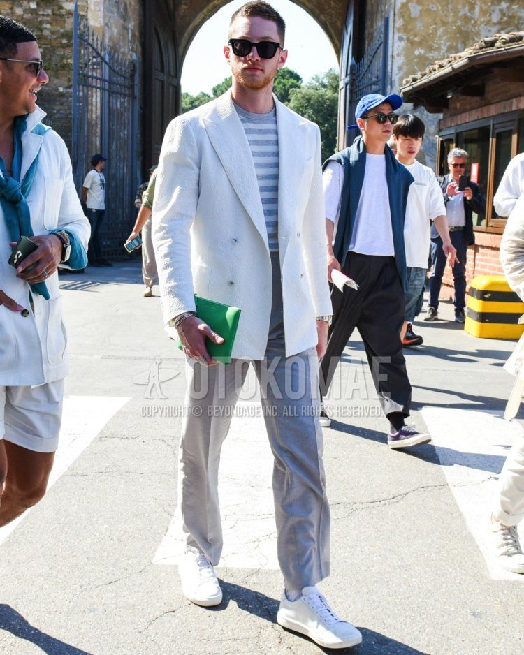 Men's spring/summer outfit and outfit with plain black sunglasses, plain white tailored jacket, gray striped t-shirt, plain gray slacks, plain white socks, white low-cut sneakers, and plain green clutch/second bag/drawstring bag.