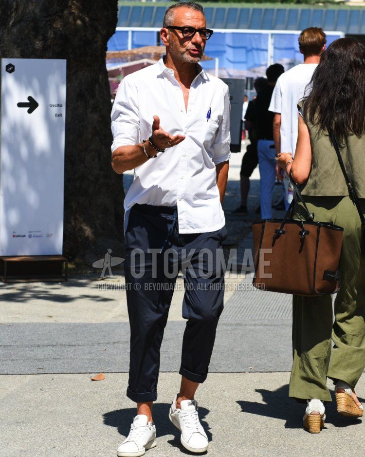 Summer/spring men's coordinate and outfit with plain black glasses, white one-pointed shirt, plain navy easy pants, and white low-cut Adidas sneakers.