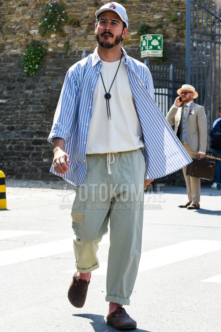 Men's spring/summer coordinate and outfit with white one-point baseball cap, clear plain glasses, plain white t-shirt, light blue striped shirt, plain green easy pants, red socks, and Birkenstock brown leather sandals.