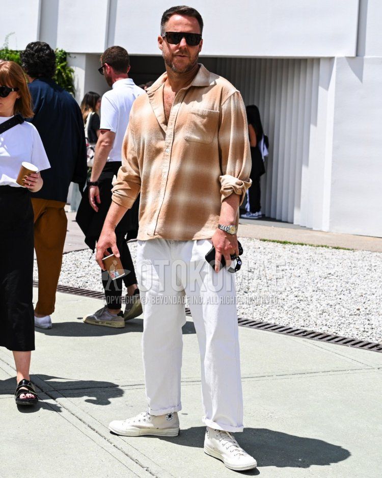 Summer/spring men's coordinate and outfit with plain black sunglasses, beige checked shirt, plain white chinos and white low-cut sneakers.