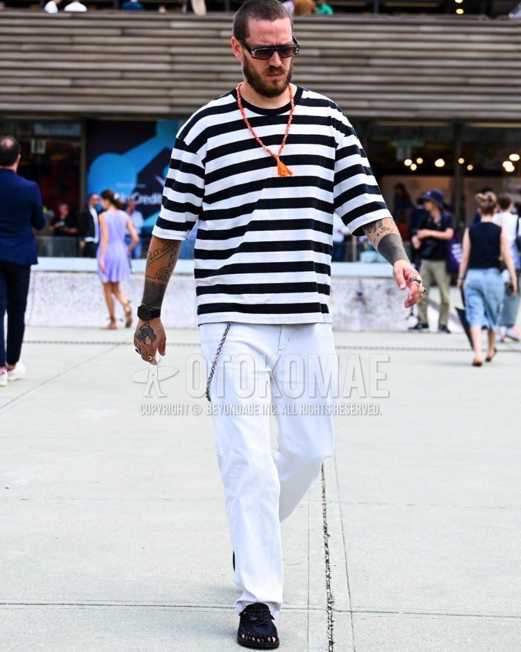 Summer/spring men's coordinate/outfit with white/black striped t-shirt, plain white denim/jeans, and black leather sandals.