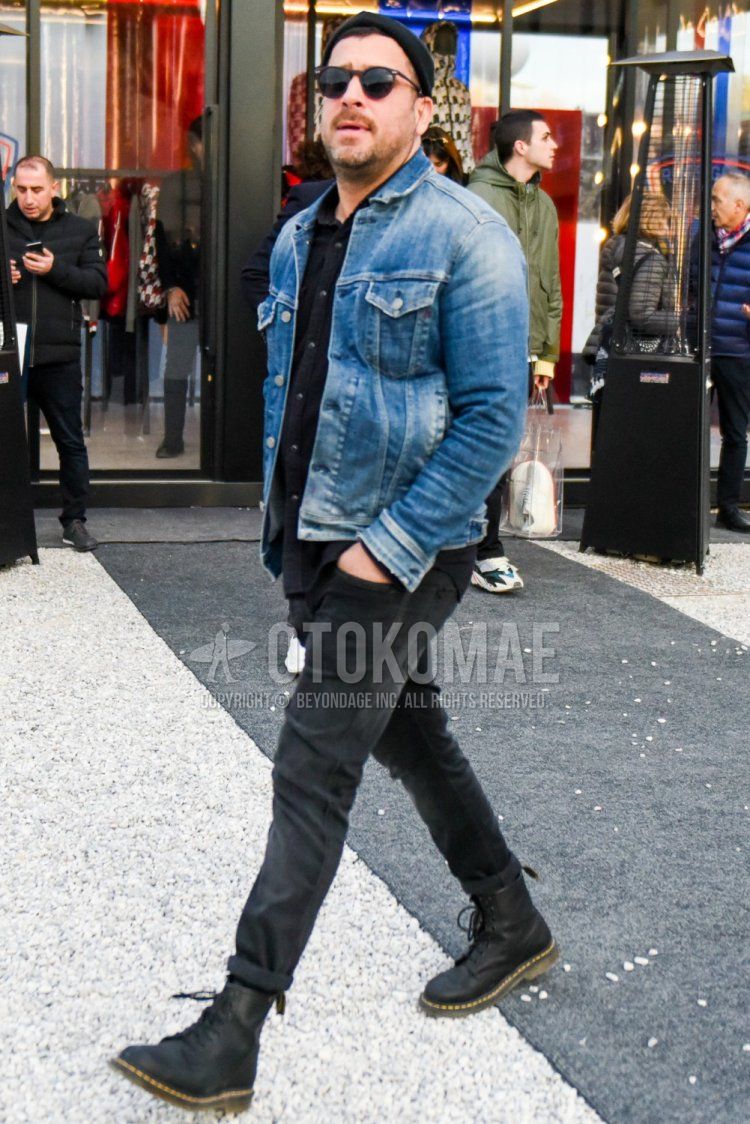 Men's spring/autumn coordinate and outfit with solid black knit cap, solid black sunglasses, solid blue denim jacket, solid black shirt, solid dark gray denim/jeans, and Dr. Martens black work boots.