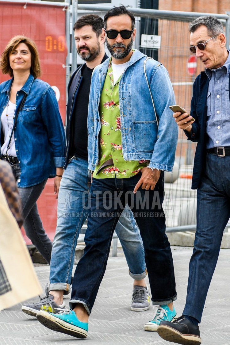 Men's spring/summer/fall coordinate and outfit with solid color sunglasses, solid color blue denim jacket, solid color white t-shirt, green top/inner shirt, solid color denim/jeans, and Converse light blue low-cut sneakers.