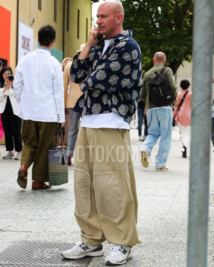 Men's fall/summer/spring coordinate and outfit with navy all-over pattern shirt, plain white t-shirt, plain beige wide-leg pants, and white low-cut sneakers by New Balance.