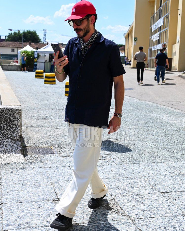 Summer/spring men's coordinate and outfit with red one-point baseball cap, plain black sunglasses, plain black scarf, plain navy shirt, plain white slacks, and black low-cut sneakers.