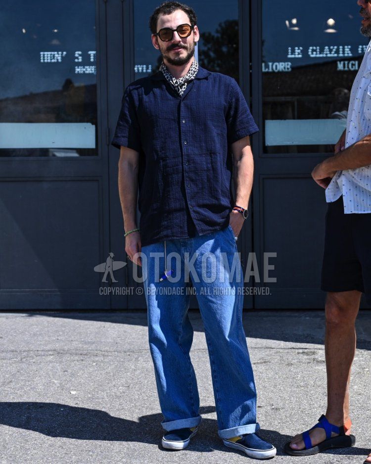 Men's spring/summer coordinate and outfit with plain brown sunglasses, all-over white bandana/neckerchief, plain navy shirt, plain light blue denim/jeans, and blue slip-on sneakers.