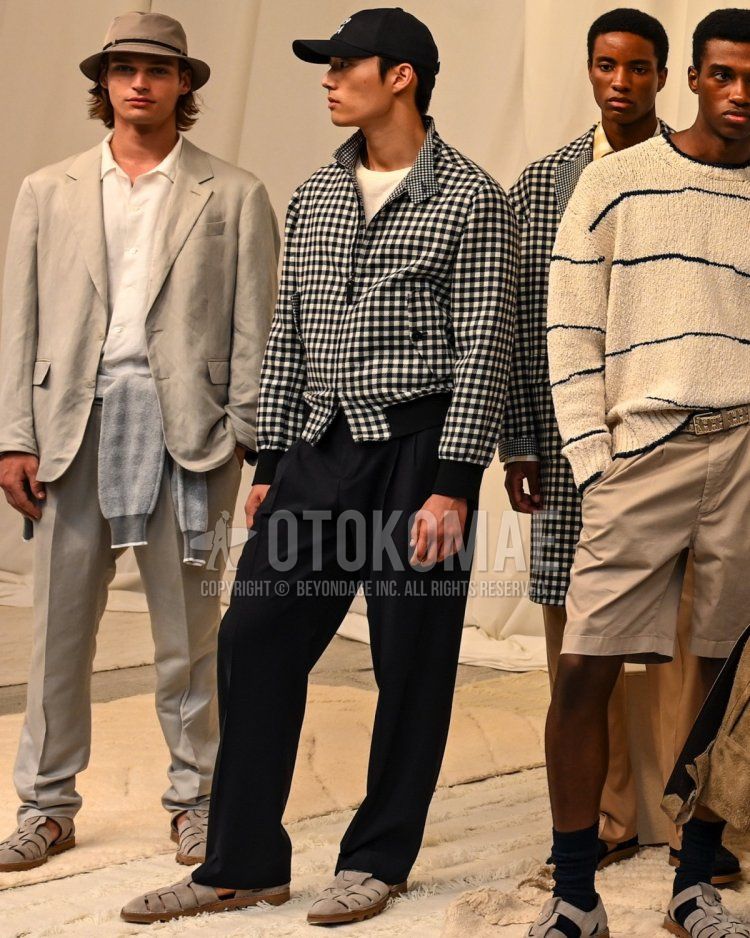 Men's spring, summer, and fall coordination and outfit with black one-pointed baseball cap, white and black checked swing top, plain white t-shirt, plain black pleated pants, and beige gluka sandals.