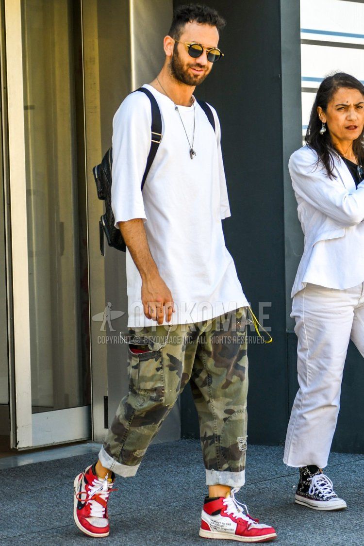 Men's spring/summer coordinate and outfit with plain sunglasses, plain white t-shirt, multi-colored camouflage cargo pants, and Nike red high-cut sneakers.