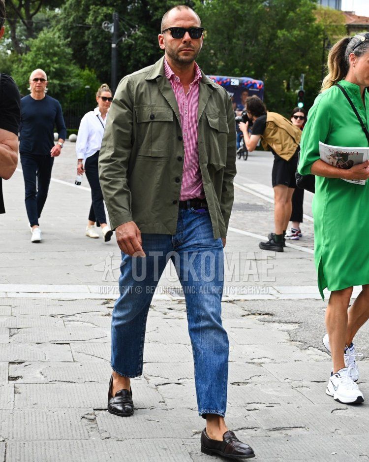 Men's fall/summer/spring coordinate and outfit with plain black sunglasses, plain olive green shirt jacket, red checked shirt, plain black leather belt, plain blue denim/jeans, and brown coin loafer leather shoes.