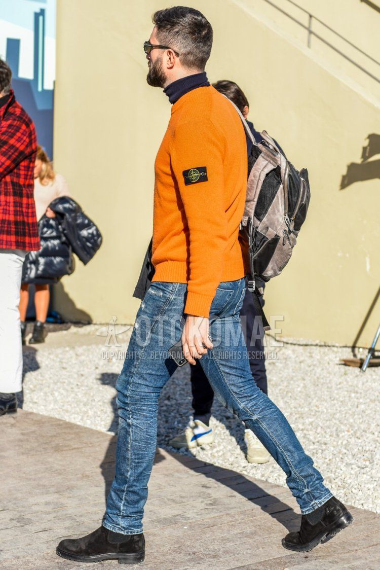 Men's spring and fall coordinate and outfit with plain black sunglasses, plain orange sweater from Stone Island, plain navy turtleneck knit, plain blue damaged jeans, and suede black side gore boots.