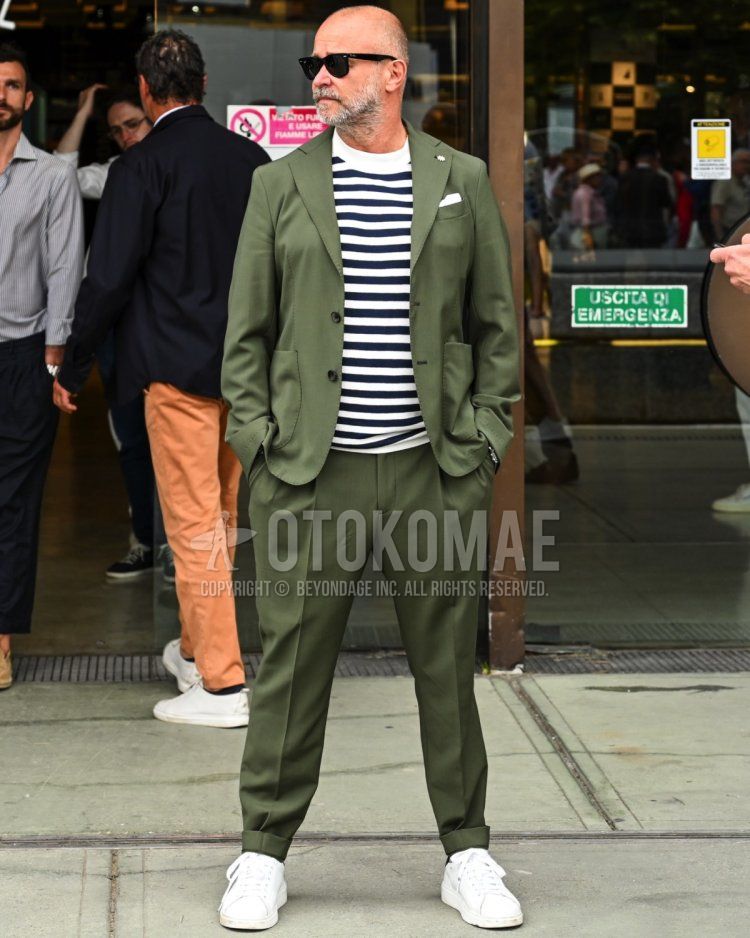 Men's spring, summer, and fall coordination and outfit with plain black sunglasses, white striped T-shirt, white low-cut sneakers, and plain green suit.