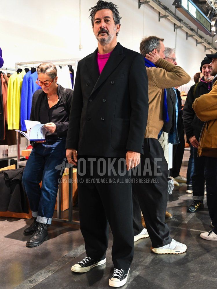 Men's winter/autumn coordinate and outfit with plain pink sweater, black low-cut Converse sneakers, and plain black suit.