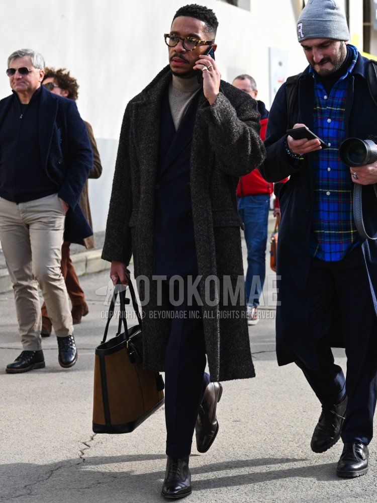Men's fall/winter coordinate and outfit with yellow tortoiseshell glasses, dark gray solid color chester coat, beige solid color turtleneck knit, brown straight tip leather shoes, brown solid color tote bag, and navy solid color suit.