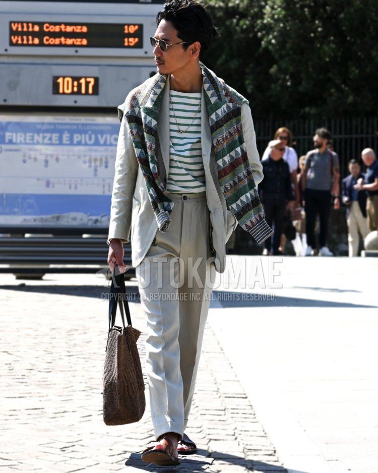 Men's spring, summer, and fall coordinate and outfit with plain black sunglasses, green striped t-shirt, green all-over sweater, brown leather sandals, plain brown tote bag, and plain white suit.