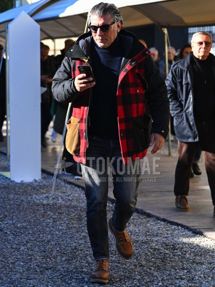 Men's fall/winter outfit with plain black sunglasses, red/black/yellow checked hooded coat, plain red/black windbreaker, plain navy/yellow turtleneck knit, plain black denim/jeans, and brown work boots.