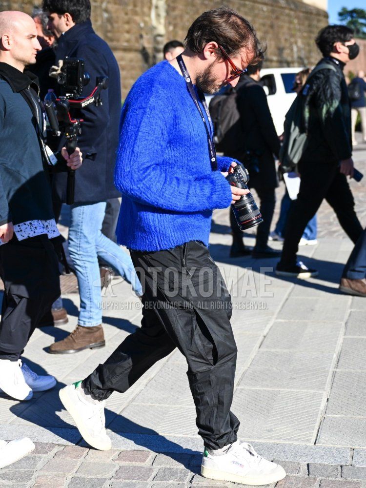 Men's fall/winter/spring coordinate and outfit with brown tortoiseshell sunglasses, solid blue sweater, solid black cargo pants, solid white socks, and white low-cut sneakers by Autry.