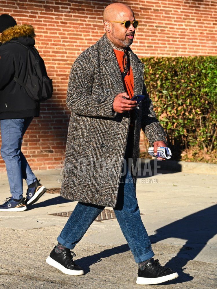 Men's fall/winter coordinate and outfit with plain yellow sunglasses, brown small patterned scarf, brown checked chester coat, plain orange sweater, plain blue winter pants (corduroy,velour), multi-colored socks socks, black low-cut sneakers.