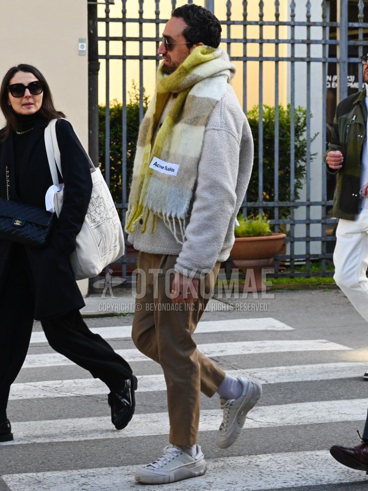 Men's fall/winter coordinate and outfit with plain black sunglasses, yellow striped scarf/stall, plain white fleece jacket, plain beige chinos, plain white socks, and white low-cut sneakers.