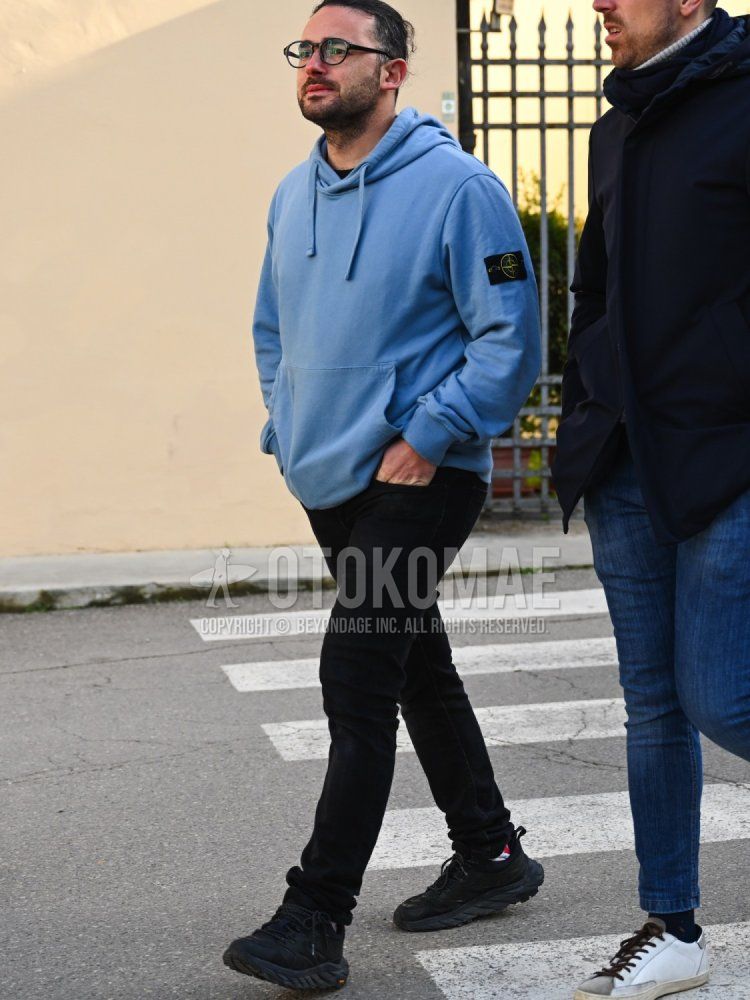 Men's fall/winter coordinate and outfit with plain black glasses, plain blue hoodie from Stone Island, plain black skinny pants, and black low-cut sneakers.