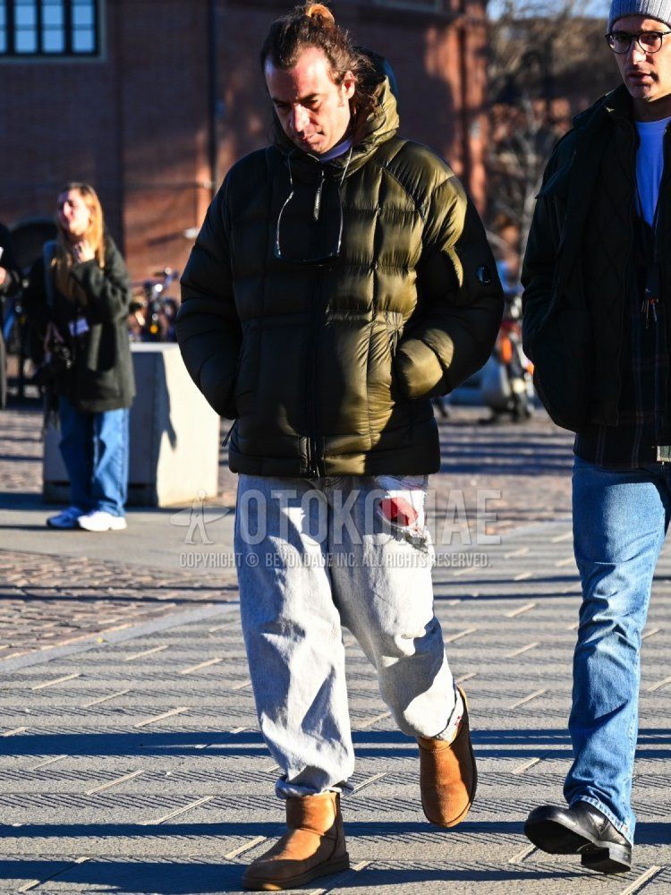 Men's fall/winter coordinate and outfit with olive green solid color down jacket, white solid color T-shirt, blue solid color damaged jeans, and brown boots.