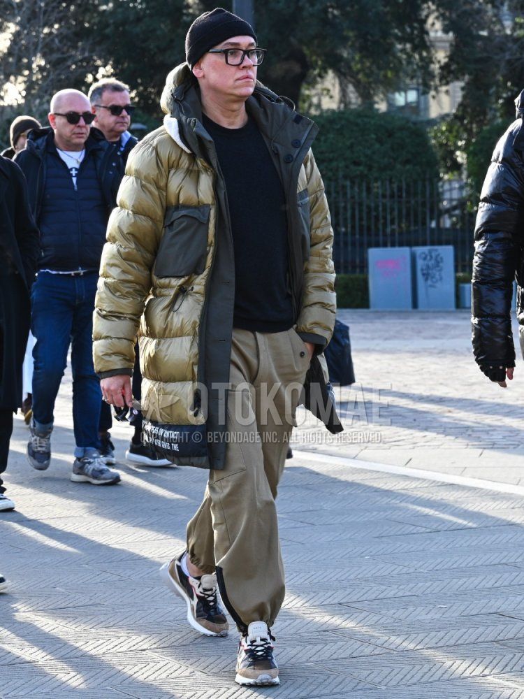 Men's fall/winter coordinate and outfit with solid black knit cap, solid black glasses, solid gold down jacket, solid gray hooded coat, solid black sweater, solid beige cargo pants, and brown low-cut sneakers.