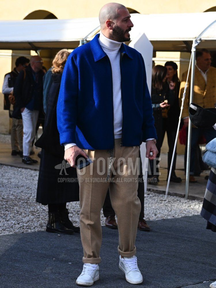 Men's fall/winter coordinate and outfit with plain navy coveralls, plain white turtleneck knit, plain beige slacks, and white low-cut sneakers.