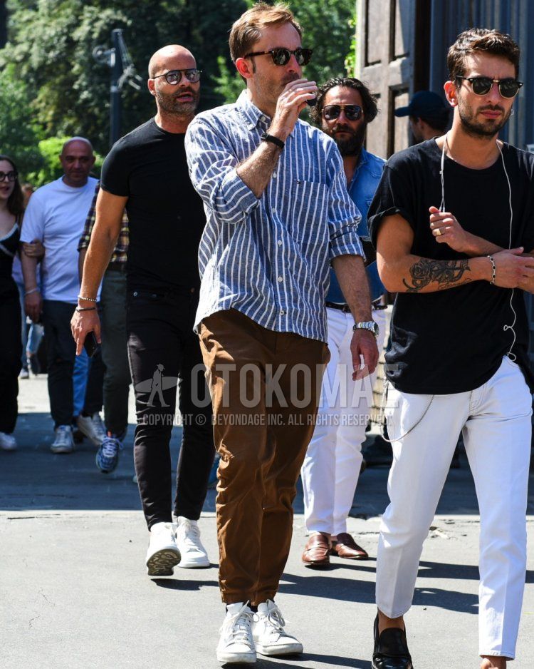 Summer/spring men's coordinate and outfit with brown tortoiseshell sunglasses, navy/white striped shirt, plain brown jogger pants/ribbed pants, plain black socks, and white low-cut sneakers.