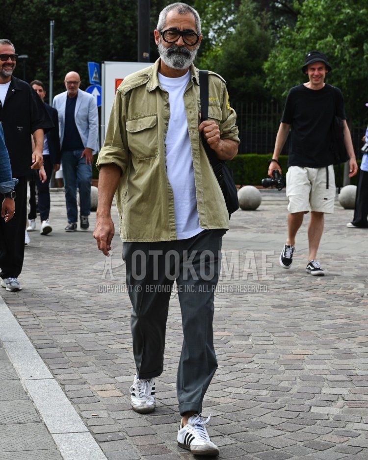 Men's summer/spring/autumn coordinate and outfit with plain beige field jacket/hunting jacket, plain white t-shirt, plain gray slacks, and white low-cut sneakers from Adidas.