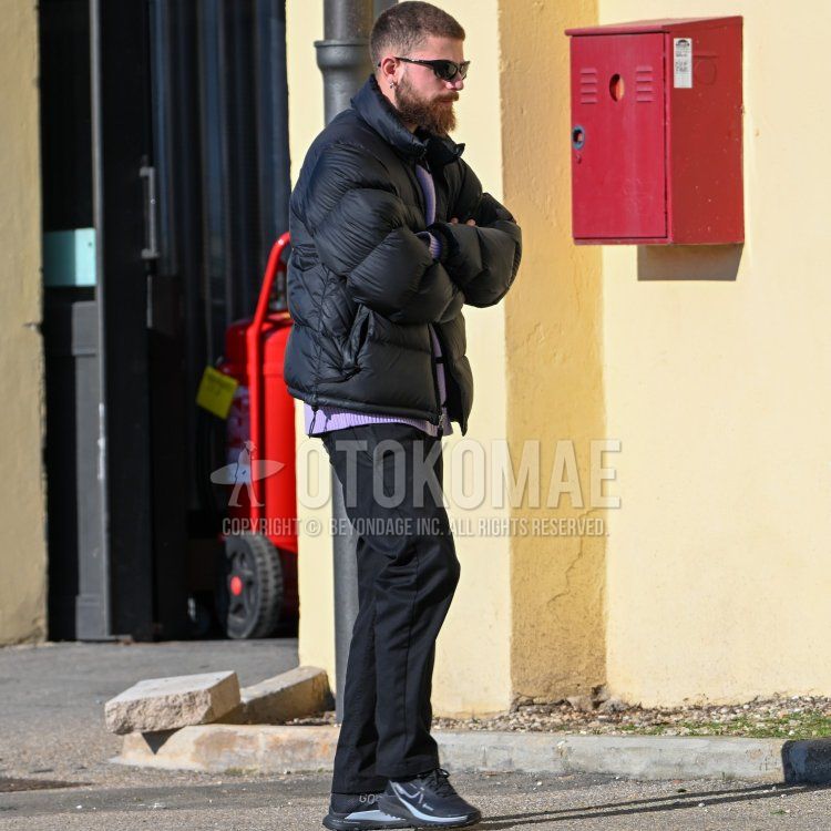 Men's fall/winter coordinate and outfit with solid black sunglasses, solid navy down jacket, solid purple sweater, solid black chinos, and black low-cut sneakers.