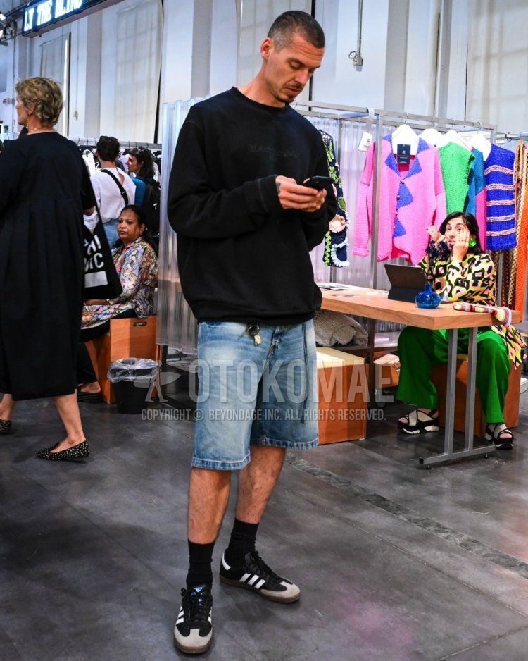 Men's spring/summer/autumn coordinate/outfit with plain black sweatshirt, plain light blue shorts, plain light blue denim/jeans, plain black socks, and black low-cut Adidas sneakers.
