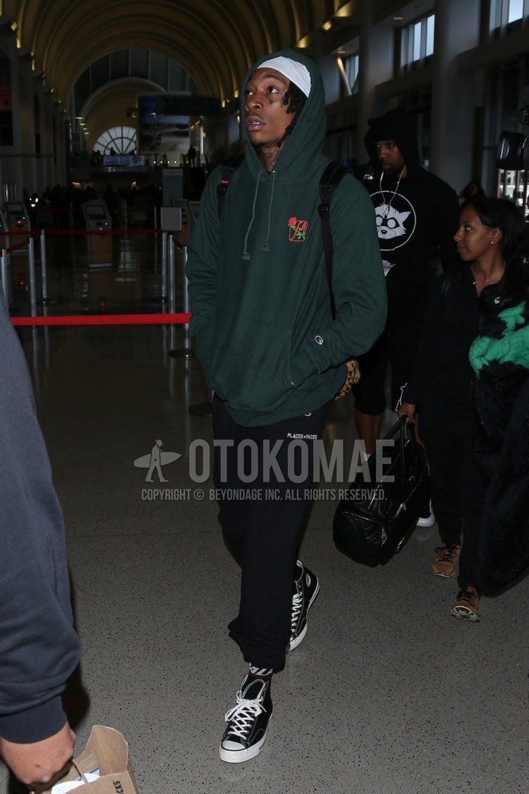 Spring men's coordinate and outfit with green one-pointed hoodie, plain black jogger pants/ribbed pants, black one-pointed socks, black high-cut Converse sneakers, and leopard backpack.