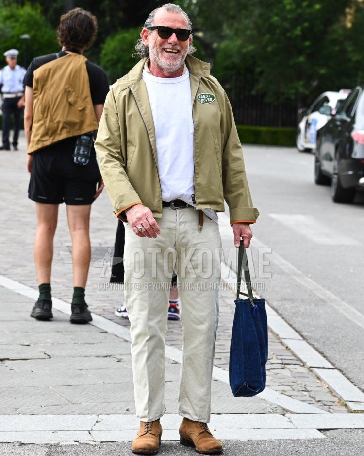 Men's fall/spring/summer outfit with plain black sunglasses, beige one-piece swing top, plain white t-shirt, plain black leather belt, plain white chinos, brown plain toe leather shoes, brown suede shoes leather shoes, plain navy tote bag.