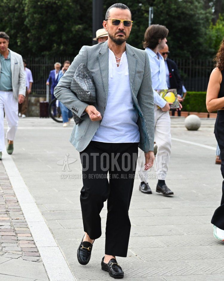 Men's fall/summer/spring outfit with plain black sunglasses, grey checked tailored jacket, plain white t-shirt, plain black slacks, Gucci black bit loafer leather shoes, grey all over clutch bag/second bag/drawstring.