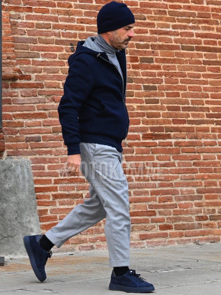 Men's fall/winter/spring outfit with solid black knit cap, solid gray turtleneck knit, solid navy hoodie, solid gray slacks, solid black socks, and navy low-cut sneakers.