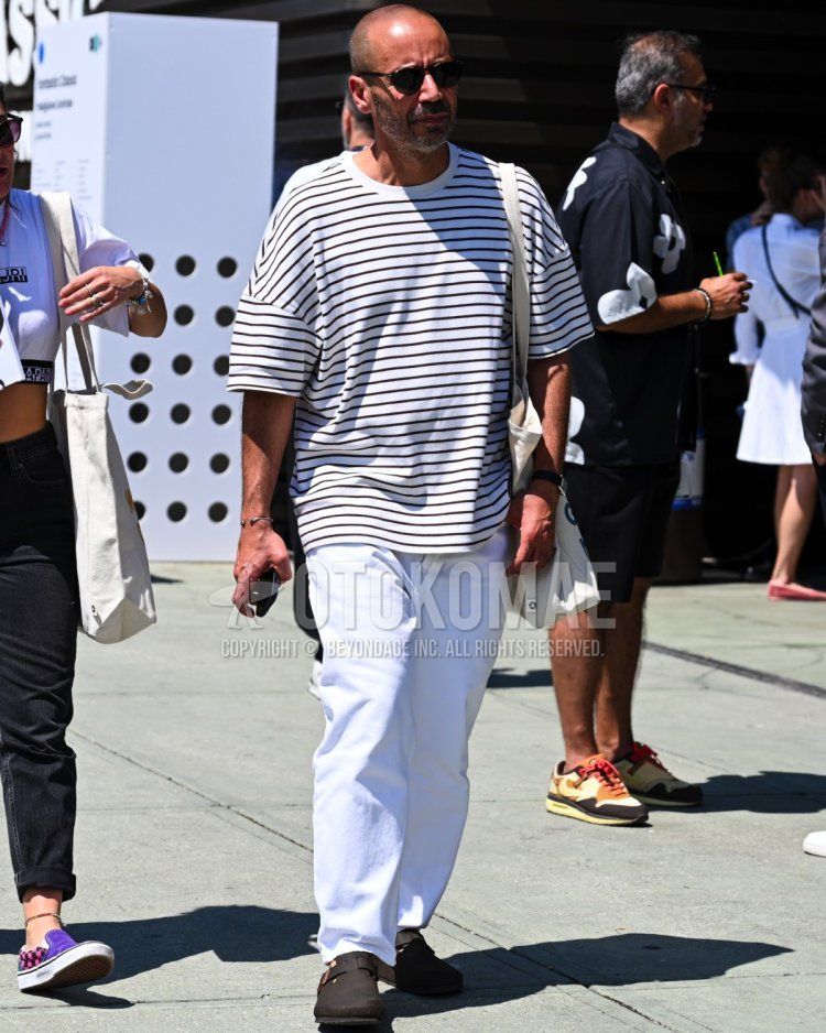Men's summer coordinate with oversized striped t-shirt, white pants and Birkenstock Boston men's summer coordinate summer coordinate tote bag slung over the shoulder.