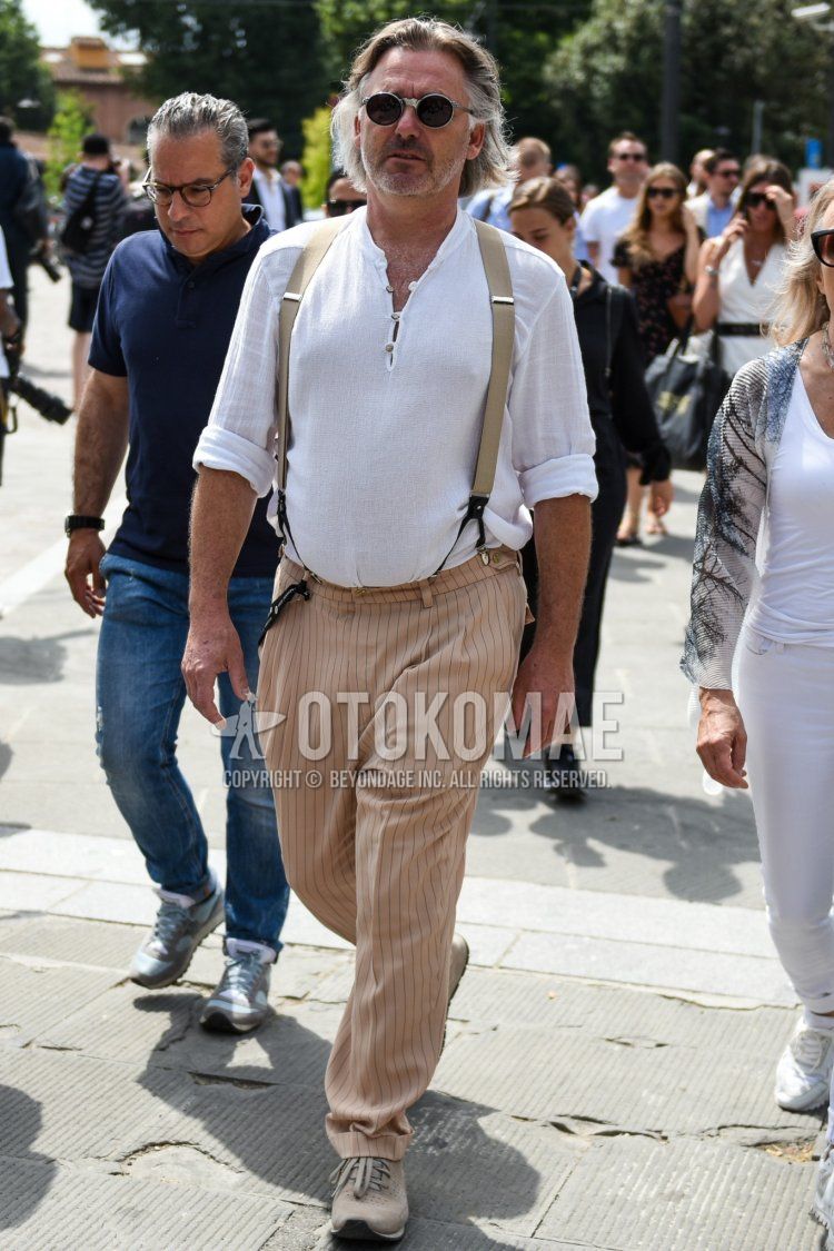 A summer men's coordinate and outfit with plain gray sunglasses, plain white t-shirt with henley neck, plain beige suspenders, beige striped slacks, and beige low-cut sneakers.