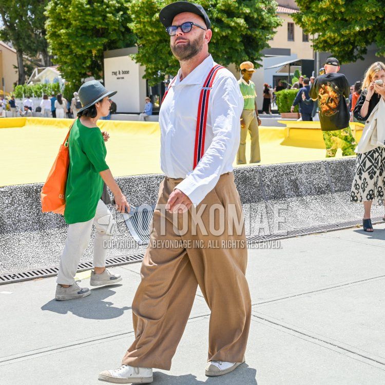 Men's fall/spring outfit with plain green baseball cap, plain blue/black sunglasses, plain white shirt, plain red/black/white suspenders, plain beige chinos, and beige/white low-cut sneakers.
