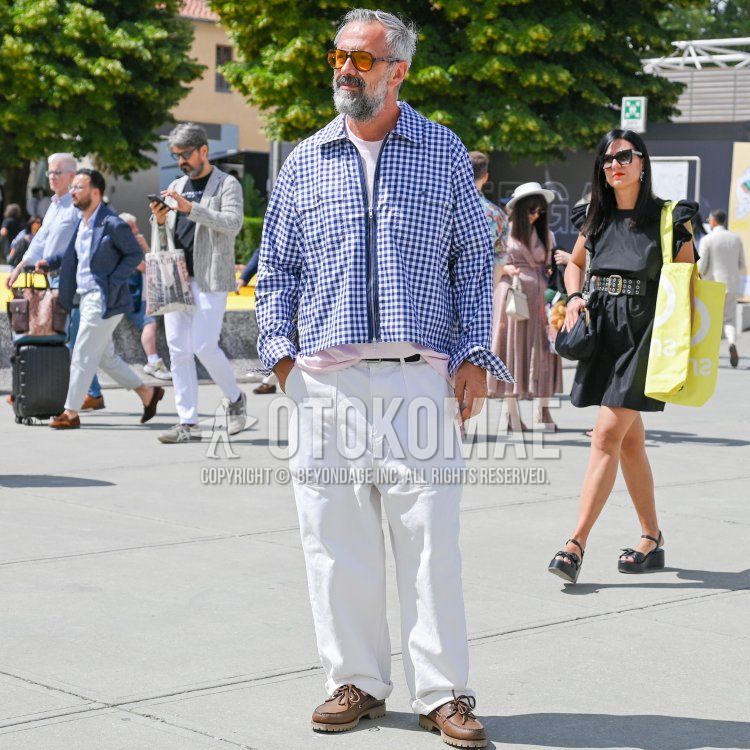 Men's fall/spring coordination and outfit with plain orange/black sunglasses, blue/white checked shirt jacket, plain pink t-shirt, plain black leather belt, plain white cotton pants, and brown moccasin/deck shoe leather shoes.