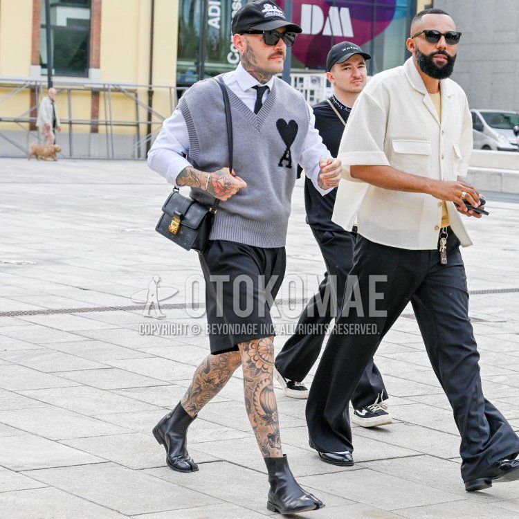 Men's spring/summer coordinate and outfit with black/white graphic baseball cap, plain white shirt, plain gray gilet from Ami Paris, plain dark gray shorts, black boots from Maison Margiela, black small print shoulder bag, and plain black tie.