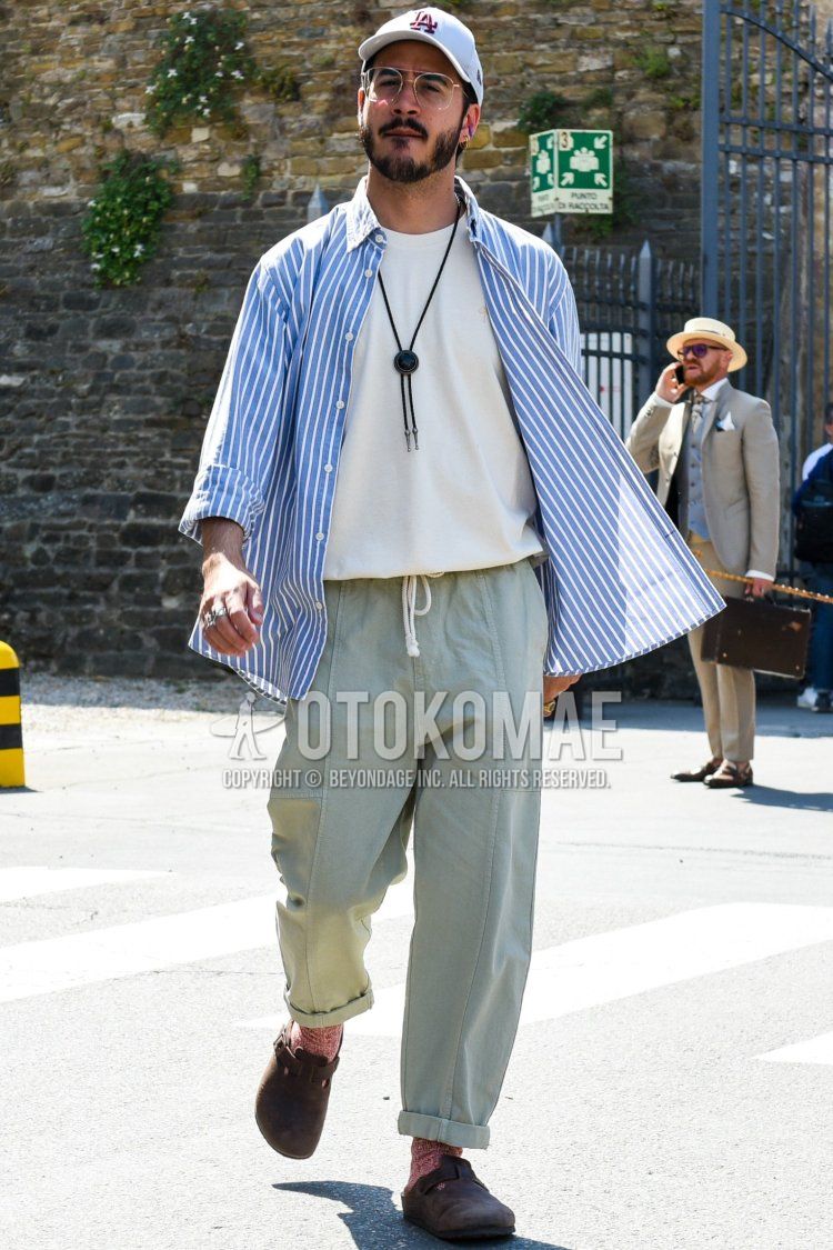 Men's spring/summer coordinate and outfit with white one-point baseball cap, clear plain glasses, plain white t-shirt, light blue striped shirt, plain green easy pants, red socks, and Birkenstock brown leather sandals.