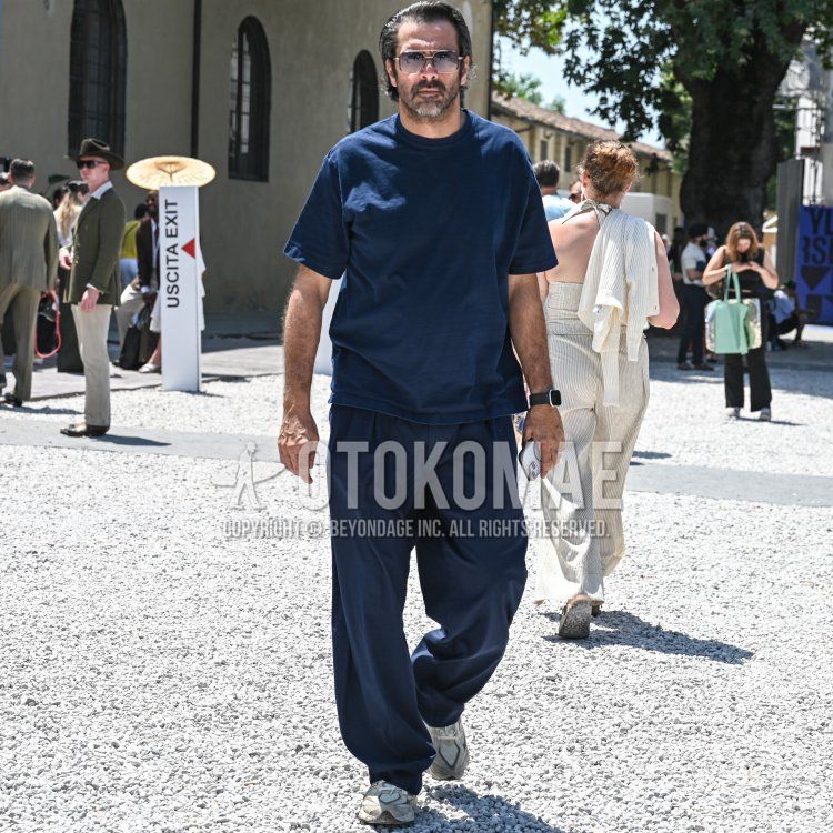 Summer/spring men's coordinate and outfit with plain silver sunglasses, plain navy t-shirt, plain navy slacks, plain navy pleated pants, and white low-cut sneakers.