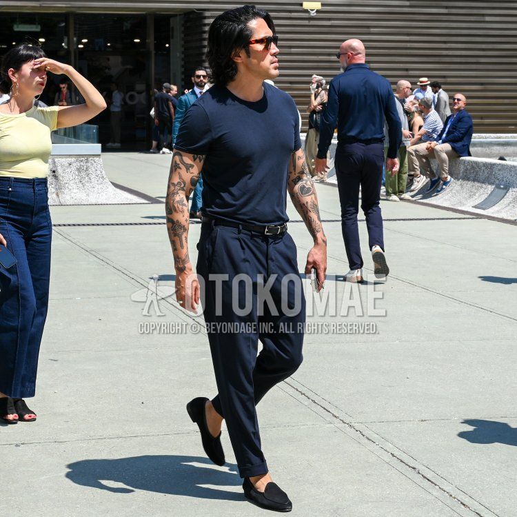 Men's spring and summer coordinate and outfit with brown tortoiseshell sunglasses, plain navy t-shirt, plain black leather belt, plain navy slacks, plain navy pleated pants, and black slip-on sneakers.