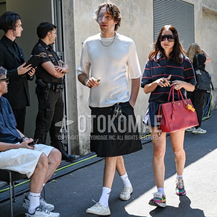 Men's spring and summer coordinate and outfit with plain white t-shirt, plain black bottoms with skirt, plain black pleated pants, plain white Adidas socks, and white low-cut sneakers.