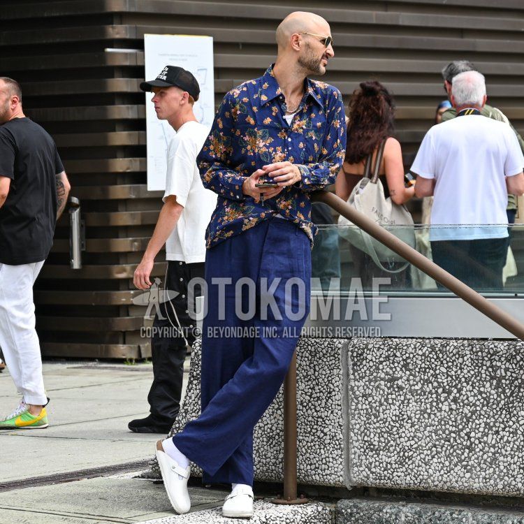 Summer/spring men's coordinate and outfit with gold plain sunglasses, navy all over shirt, white plain tank top, white plain slacks, white plain socks, and Birkenstock Boston white leather sandals.