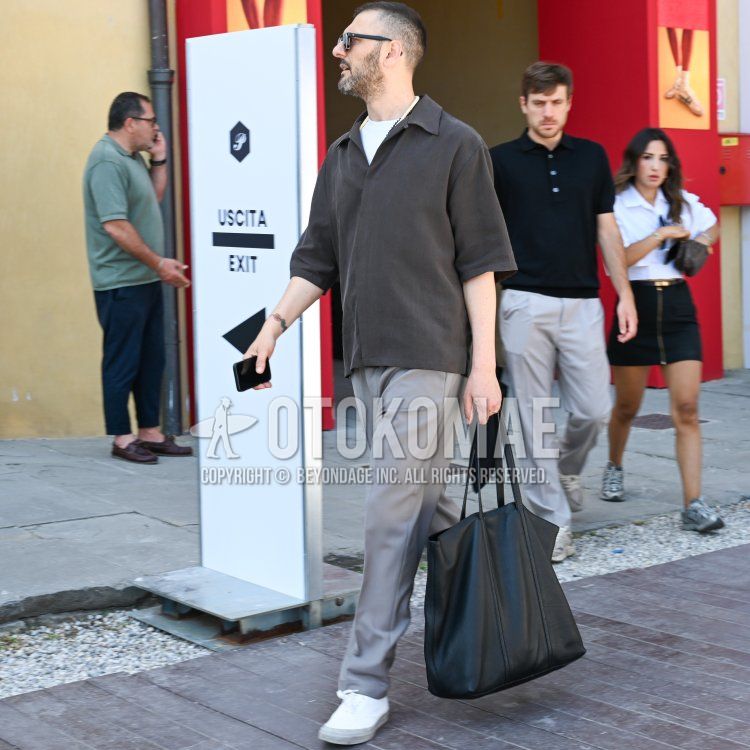 Summer/spring men's coordinate and outfit with plain black sunglasses, plain brown polo shirt, plain white t-shirt, plain gray slacks, white low-cut sneakers, and leather plain black tote bag.